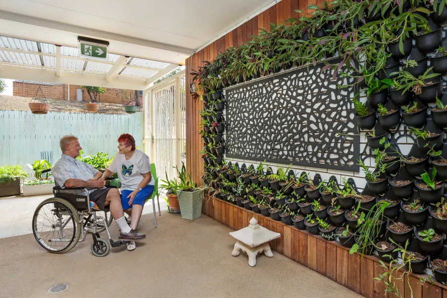 Two people beside a courtyard vertical garden at Caloundra Place Care Community.